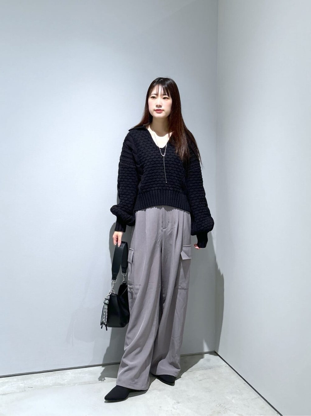 ブラック系のニット/セーター、グレー系のその他パンツ、ブラック系のショルダーバッグを着用したレディースの秋コーディネートの2枚目の写真