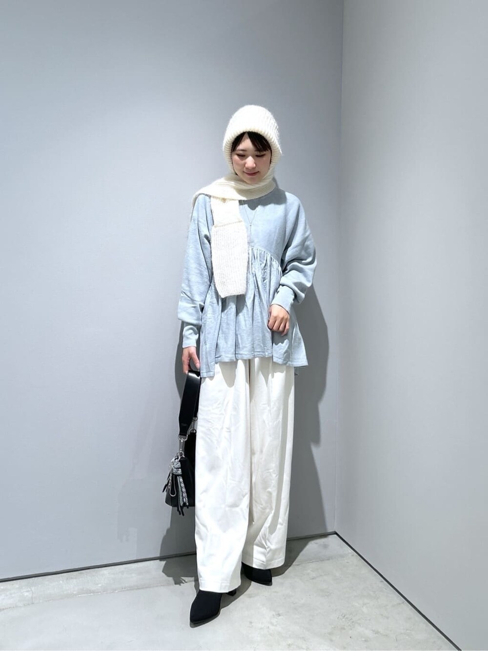 ブルー系のニット/セーター、ホワイト系のその他パンツ、ブラック系のショルダーバッグを着用したレディースの冬コーディネートの3枚目の写真