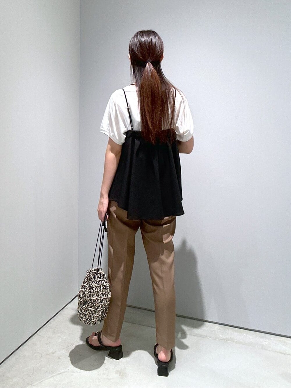 ブラック系のタンクトップ、イエロー系のその他パンツ、ブラック系のハンドバッグを着用したレディースの夏コーディネートの5枚目の写真