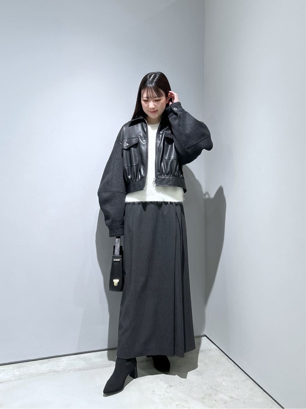 ブラック系のブルゾン、ホワイト系のニット/セーター、グレー系のスカートを着用したレディースの冬コーディネートの4枚目の写真