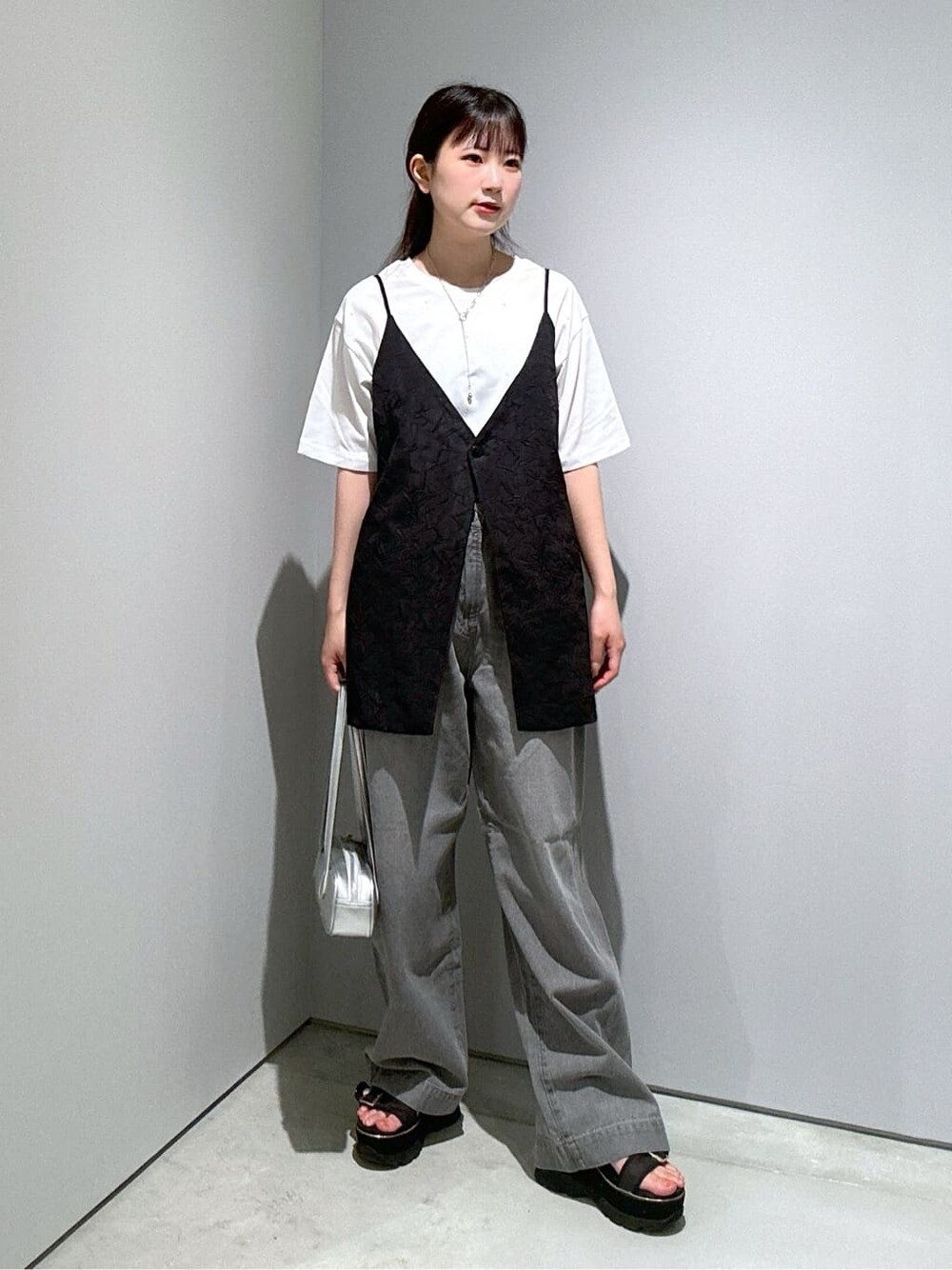 ホワイト系のTシャツ/カットソー、ブラック系のベスト、グレー系のデニムパンツを着用したレディースの夏コーディネートの4枚目の写真