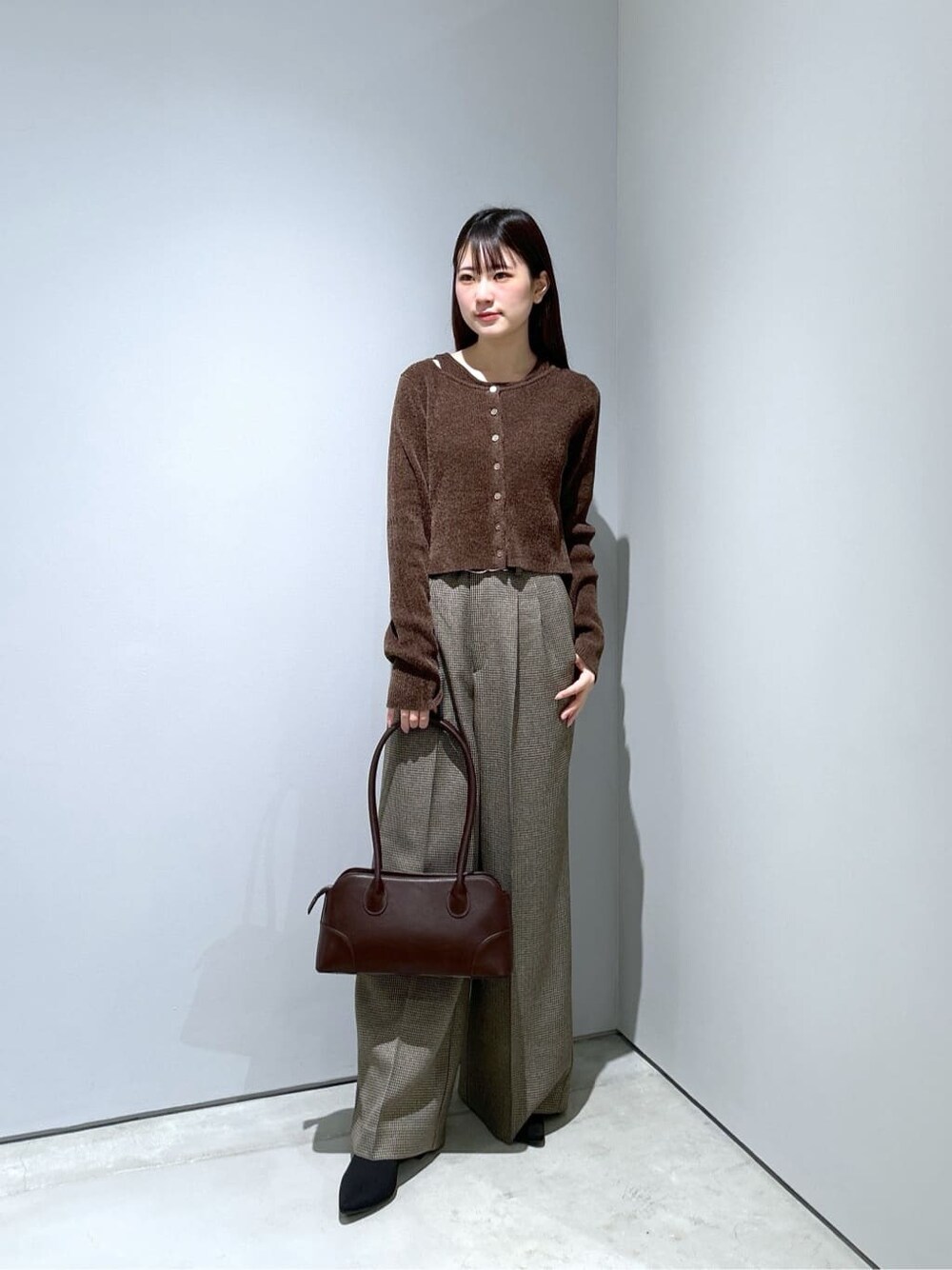 ホワイト系のチェスターコート、ブラウン系のニット/セーター、ベージュ系のその他パンツを着用したレディースの秋コーディネートの2枚目の写真