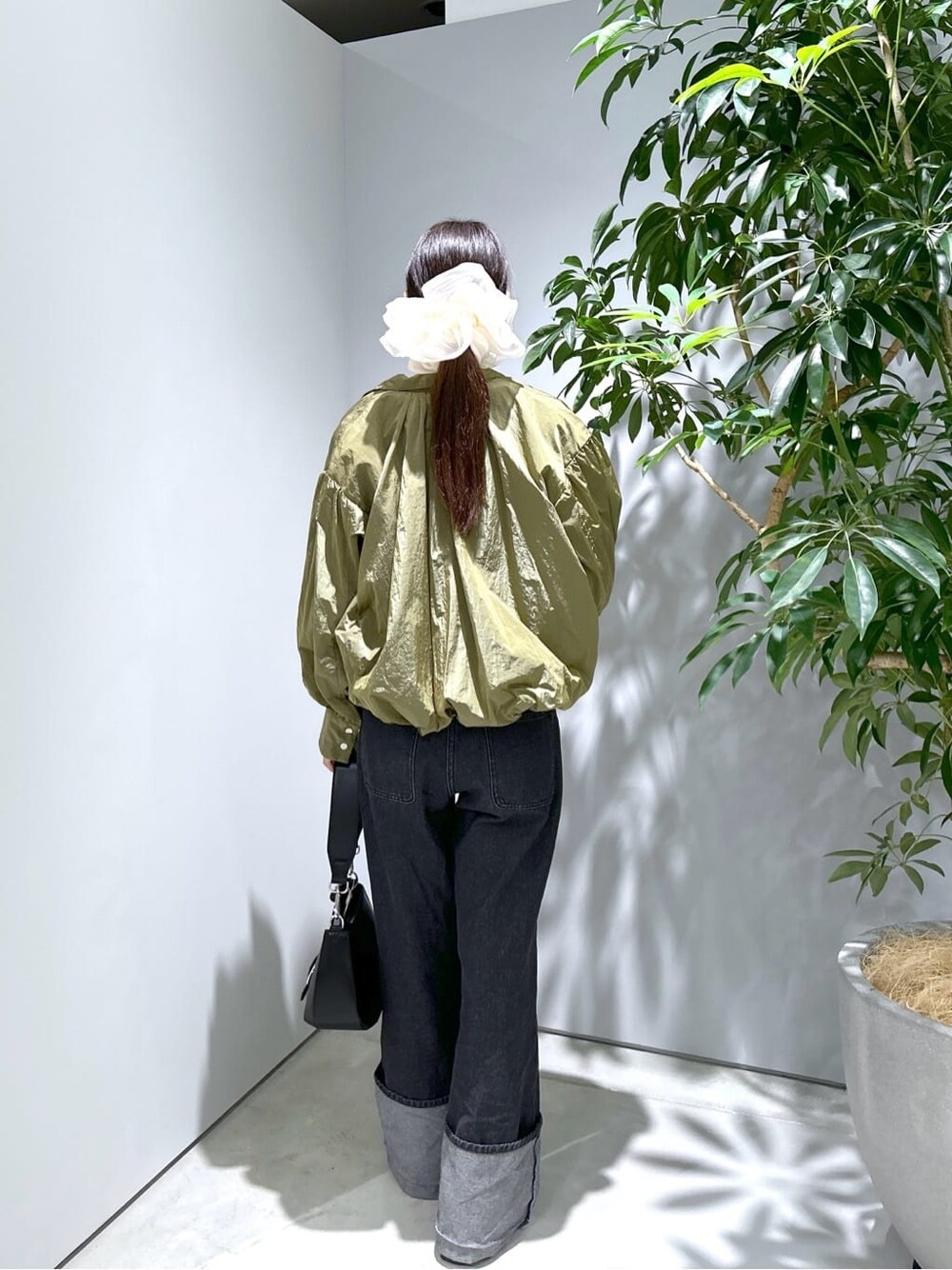 グリーン系のブルゾン、ホワイト系のTシャツ/カットソー、グレー系のデニムパンツを着用したレディースの秋コーディネートの5枚目の写真