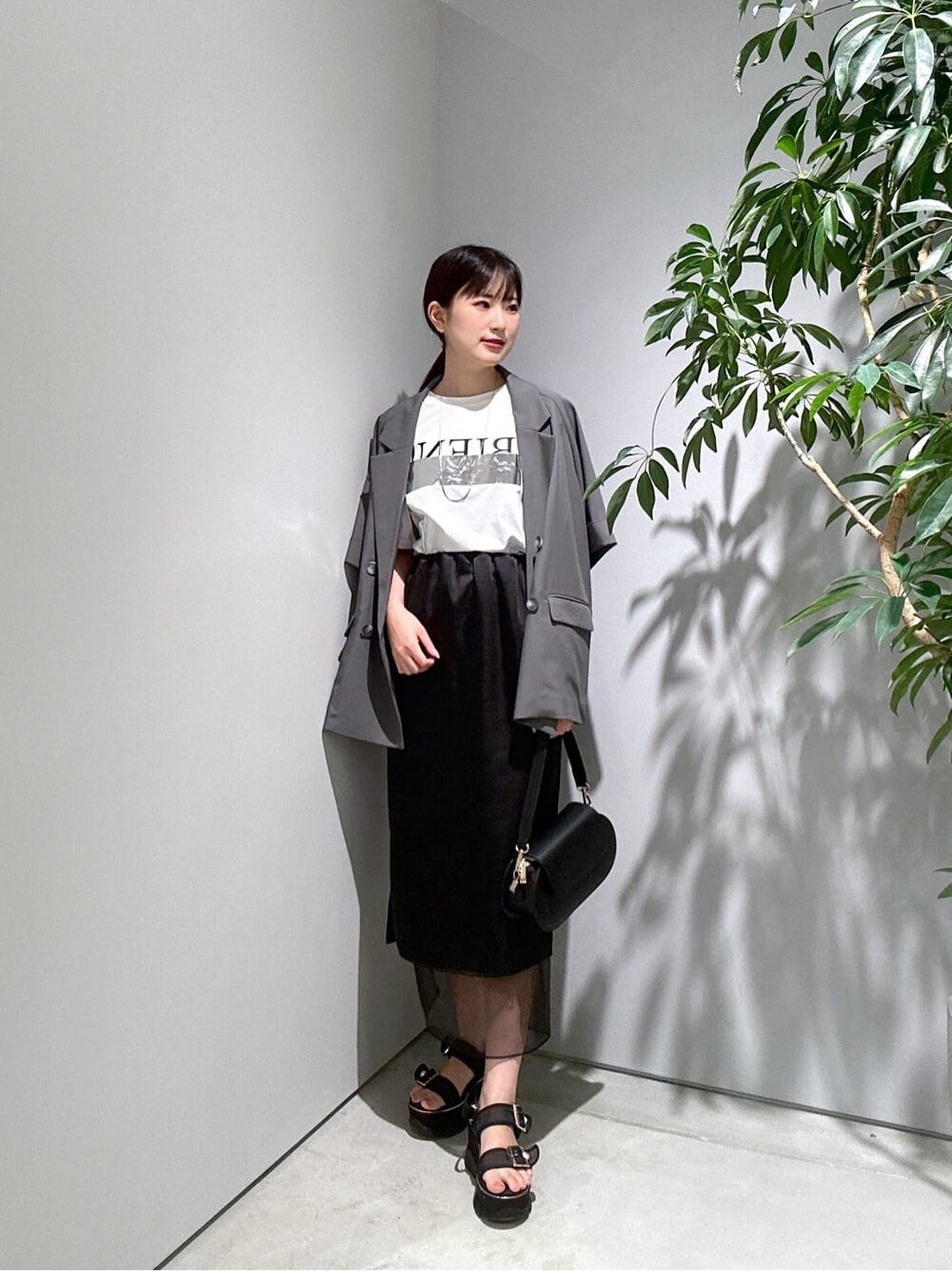 グレー系のテーラードジャケット、ホワイト系のTシャツ/カットソー、ブラック系のスカートを着用したレディースの夏コーディネートの3枚目の写真