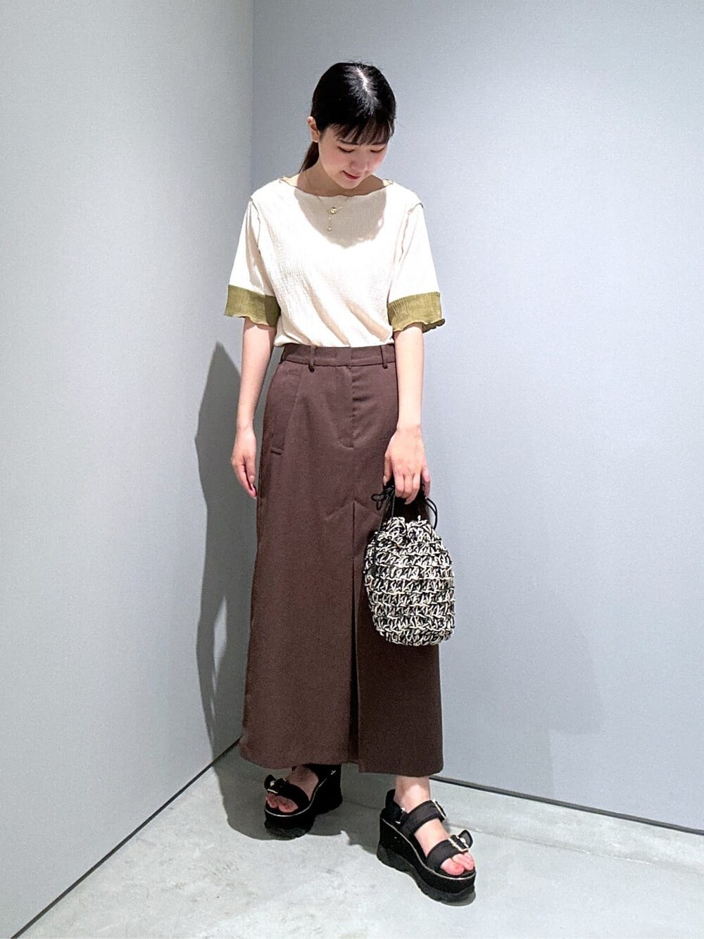 ホワイト系のTシャツ/カットソー、ブラウン系のスカート、ブラック系のハンドバッグを着用したレディースの夏コーディネートの4枚目の写真