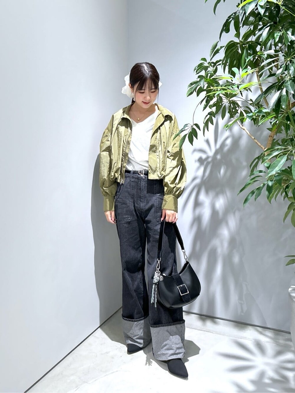 グリーン系のブルゾン、ホワイト系のTシャツ/カットソー、グレー系のデニムパンツを着用したレディースの秋コーディネートの4枚目の写真