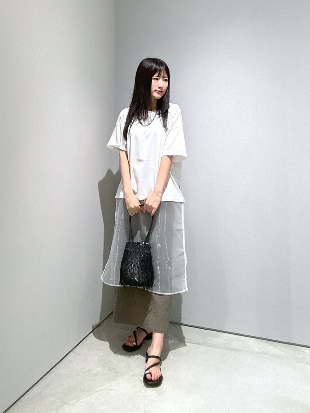 ホワイト系のTシャツ/カットソー、グリーン系のスカート、ブラック系のハンドバッグを着用したレディースの夏コーディネートの2枚目の写真