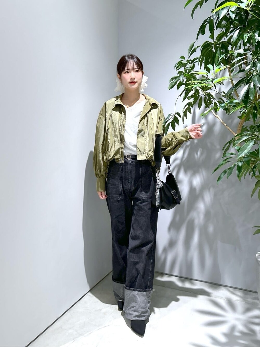 グリーン系のブルゾン、ホワイト系のTシャツ/カットソー、グレー系のデニムパンツを着用したレディースの秋コーディネートの3枚目の写真