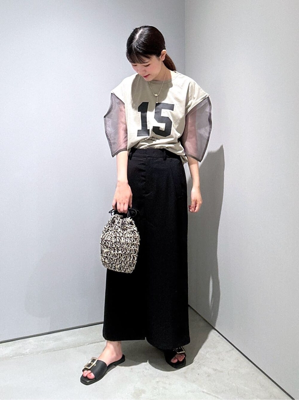 グリーン系のTシャツ/カットソー、ブラック系のスカート、ブラック系のハンドバッグを着用したレディースの夏コーディネートの5枚目の写真