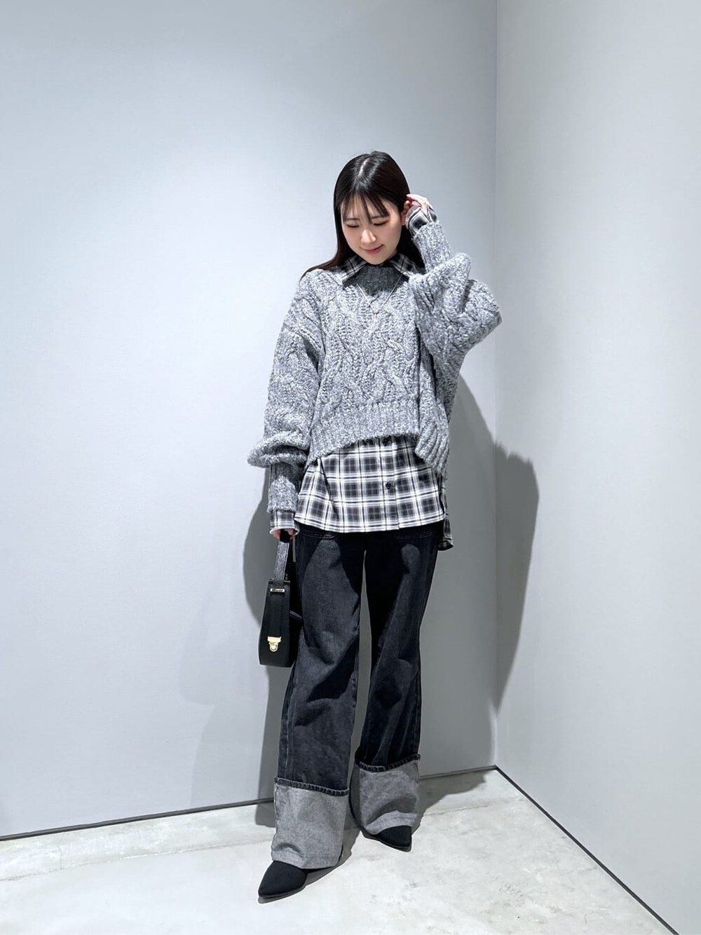 グレー系のニット/セーター、ブラック系のシャツ/ブラウス、グレー系のデニムパンツを着用したレディースの冬コーディネートの4枚目の写真