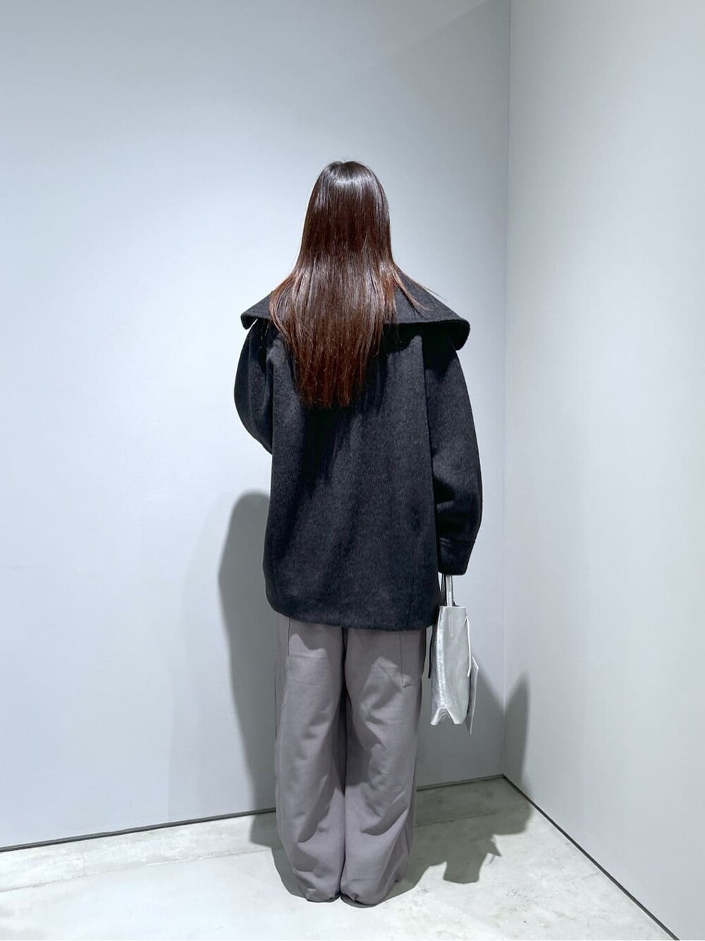グレー系のチェスターコート、ブラック系のニット/セーター、グレー系のその他パンツを着用したレディースの冬コーディネートの5枚目の写真
