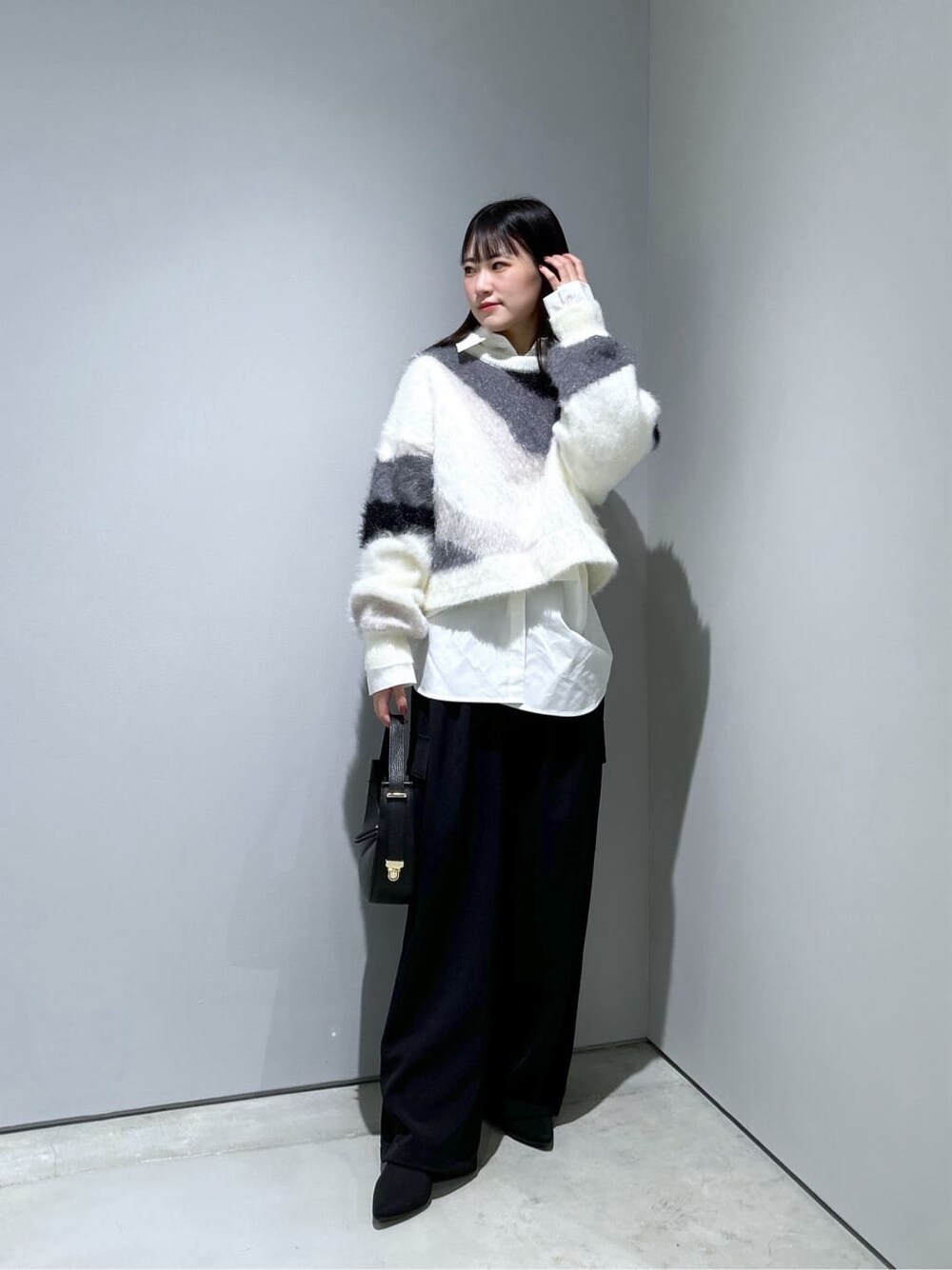 ホワイト系のニット/セーター、ホワイト系のシャツ/ブラウス、ブラック系のその他パンツを着用したレディースの冬コーディネートの2枚目の写真