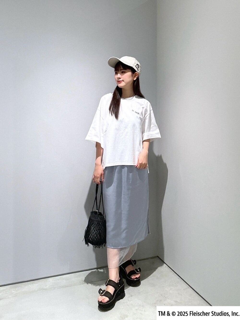 ホワイト系のTシャツ/カットソー、ブルー系のスカート、ブラック系のハンドバッグを着用したレディースの夏コーディネートの3枚目の写真