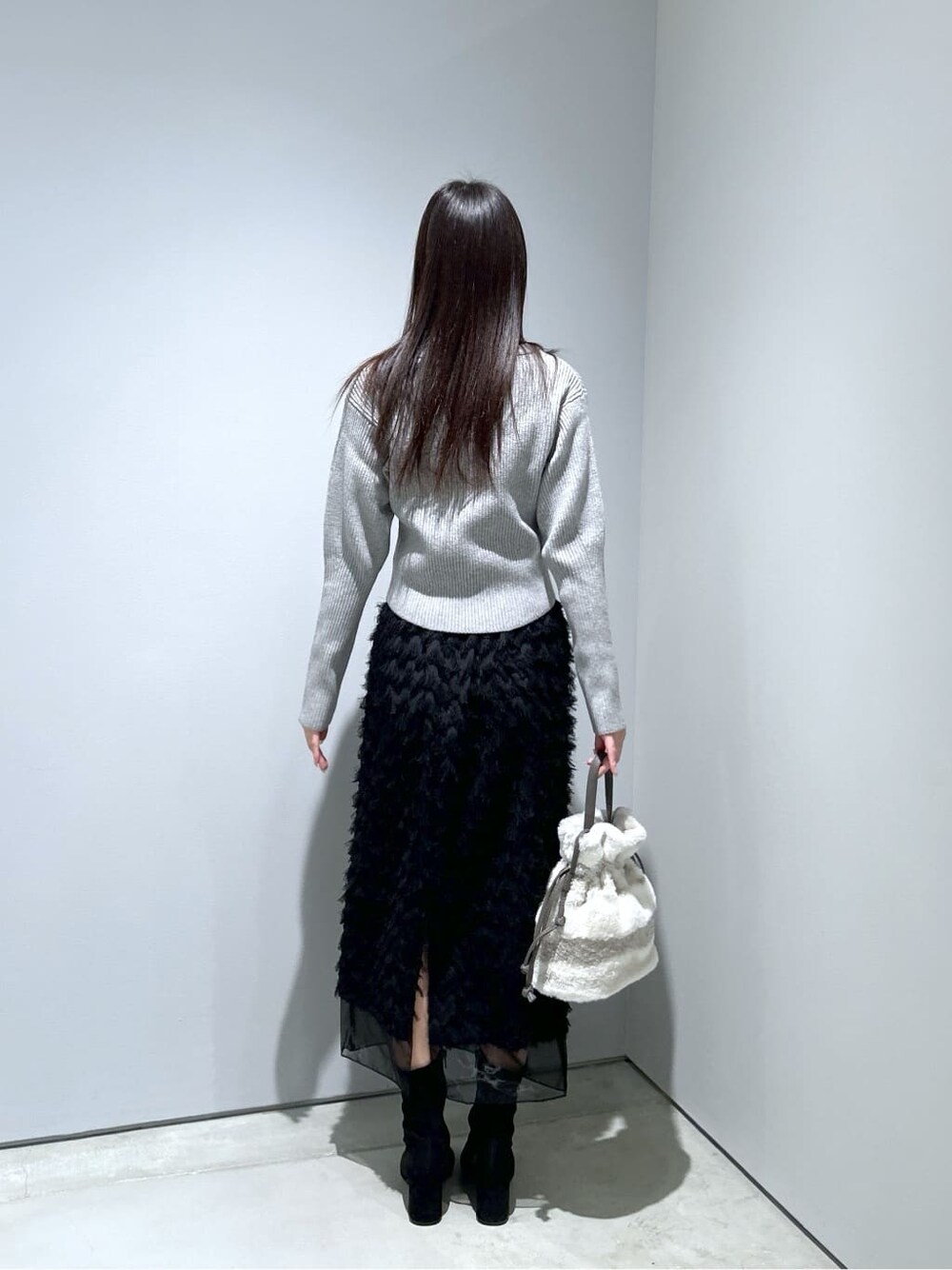 ブラック系のスカート、グレー系のショルダーバッグ、ゴールド系のネックレスを着用したレディースの冬コーディネートの5枚目の写真