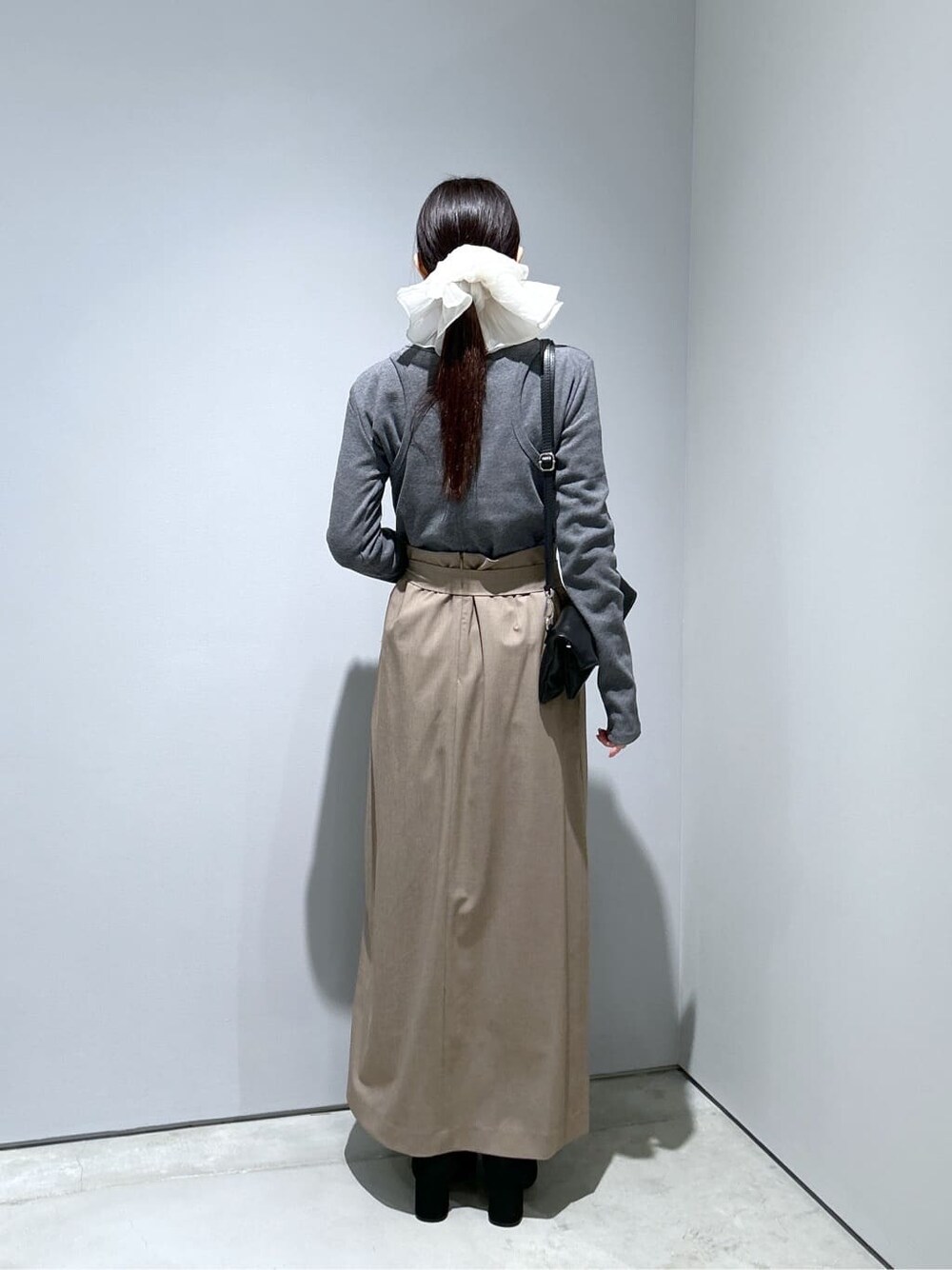 グレー系のTシャツ/カットソー、ベージュ系のスカート、ブラック系のショルダーバッグを着用したレディースの冬コーディネートの5枚目の写真