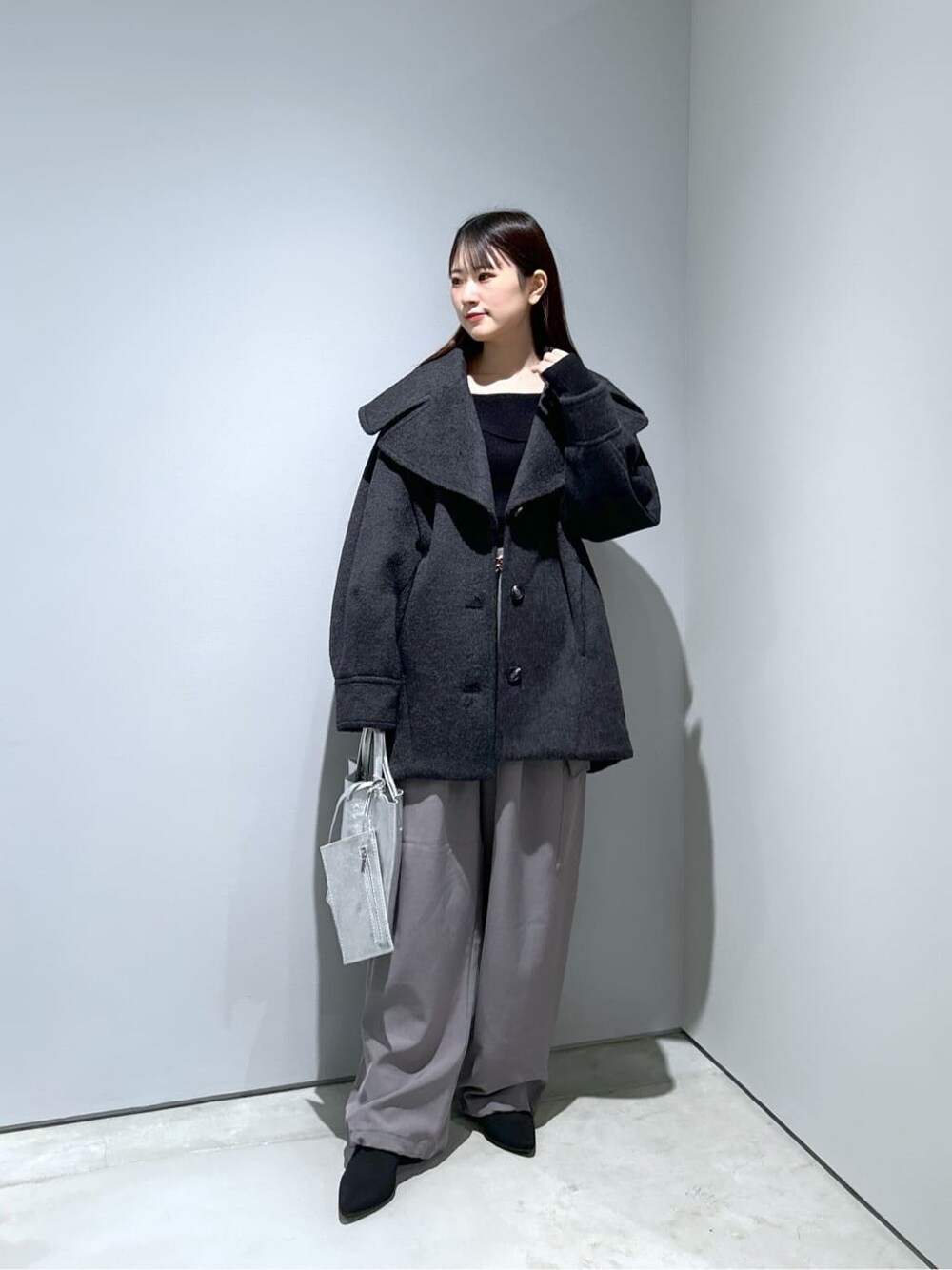 グレー系のチェスターコート、ブラック系のニット/セーター、グレー系のその他パンツを着用したレディースの冬コーディネートの3枚目の写真