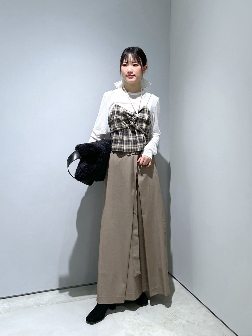 ベージュ系のタンクトップ、ホワイト系のTシャツ/カットソー、ベージュ系のスカートを着用したレディースの冬コーディネートの2枚目の写真
