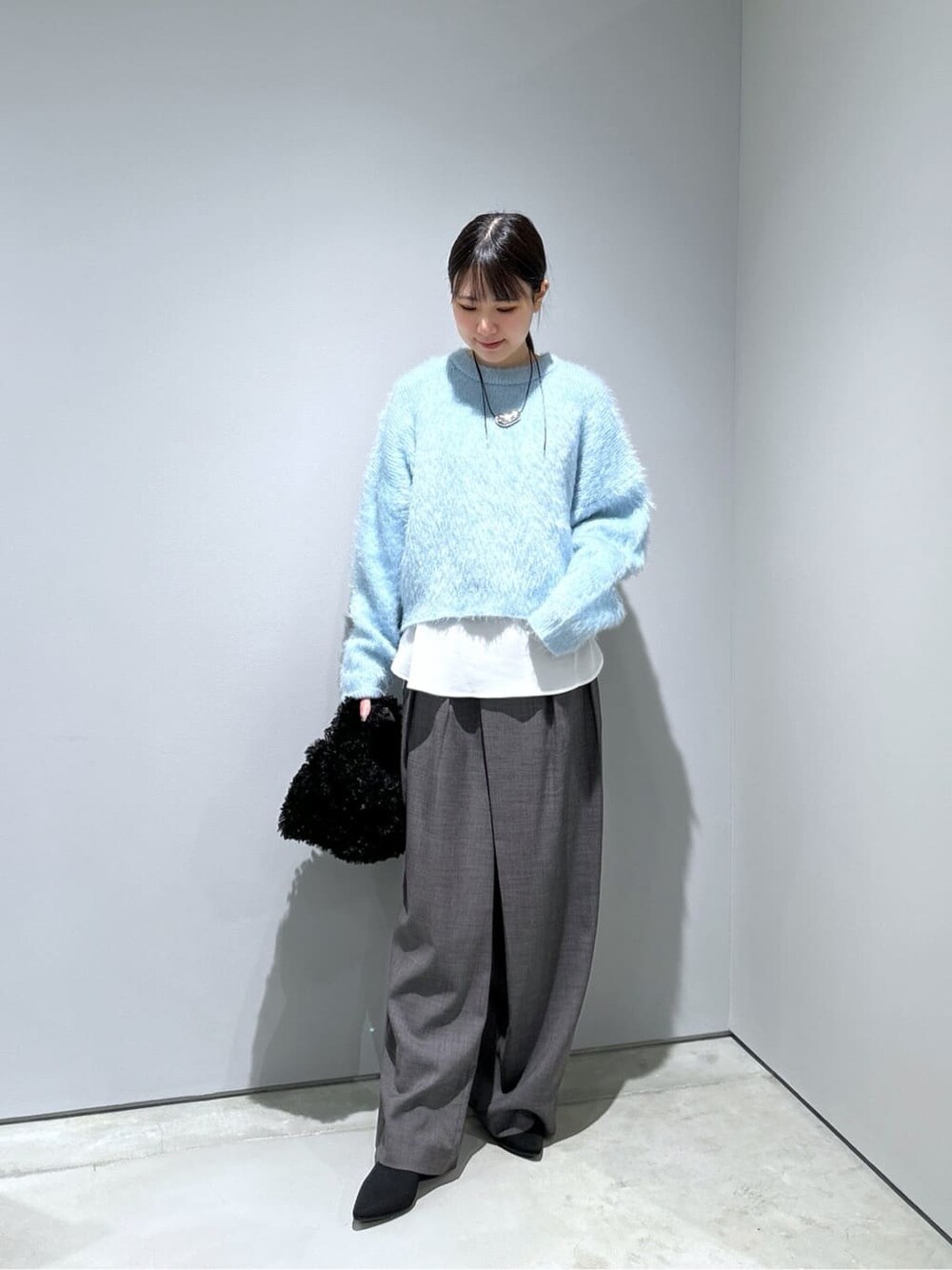 ブルー系のニット/セーター、ホワイト系のシャツ/ブラウス、グレー系のその他パンツを着用したレディースの秋コーディネートの5枚目の写真