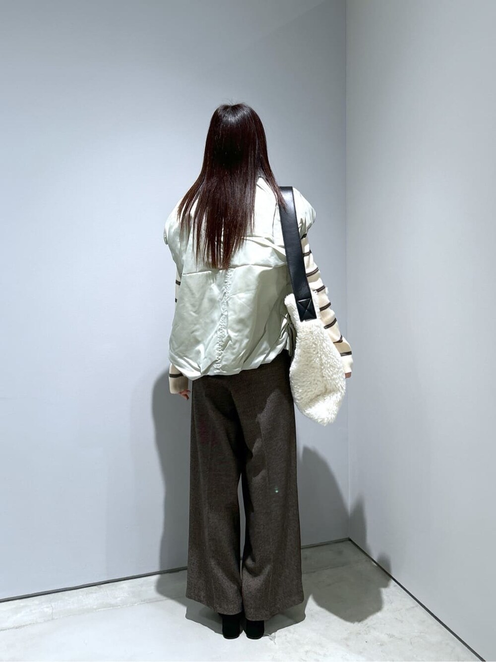 グリーン系のブルゾン、ベージュ系のニット/セーター、ブラウン系のその他パンツを着用したレディースの冬コーディネートの5枚目の写真