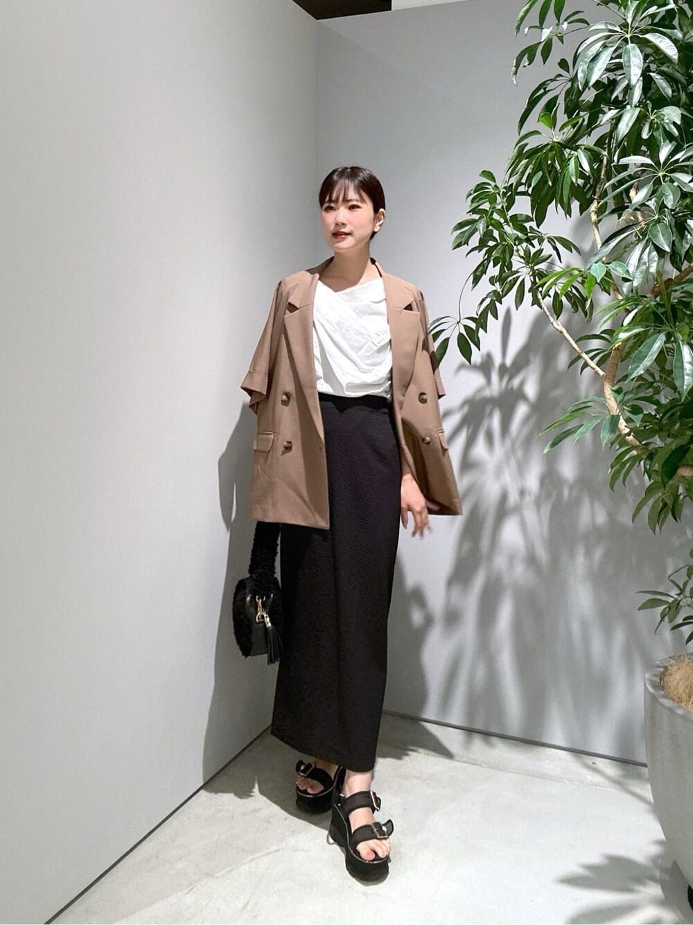 イエロー系のテーラードジャケット、ホワイト系のTシャツ/カットソー、ブラック系のスカートを着用したレディースの夏コーディネートの4枚目の写真