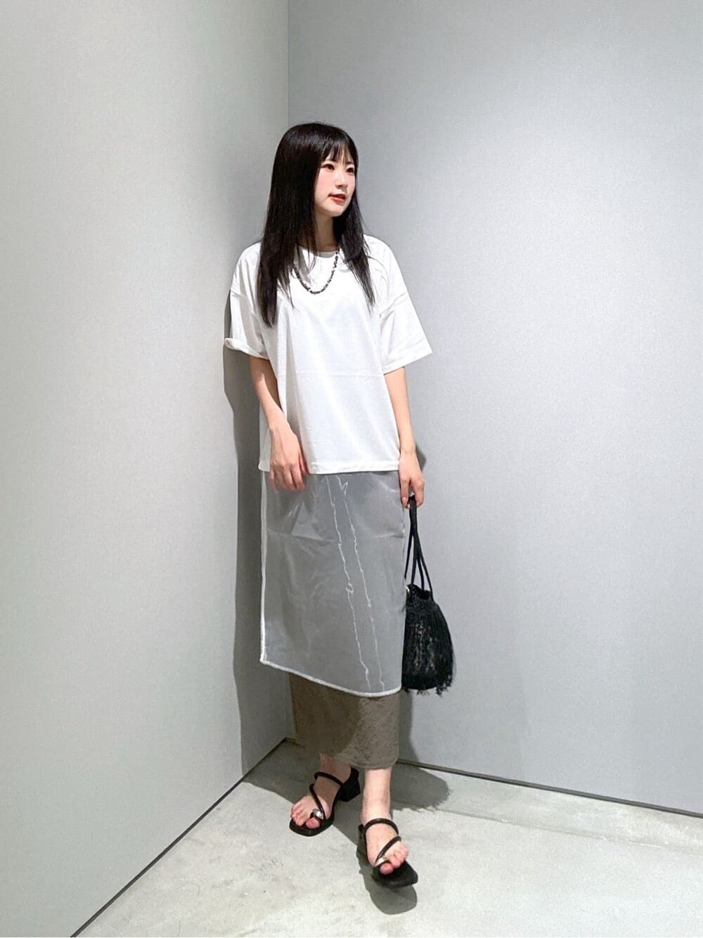 ホワイト系のTシャツ/カットソー、グリーン系のスカート、ブラック系のハンドバッグを着用したレディースの夏コーディネートの3枚目の写真
