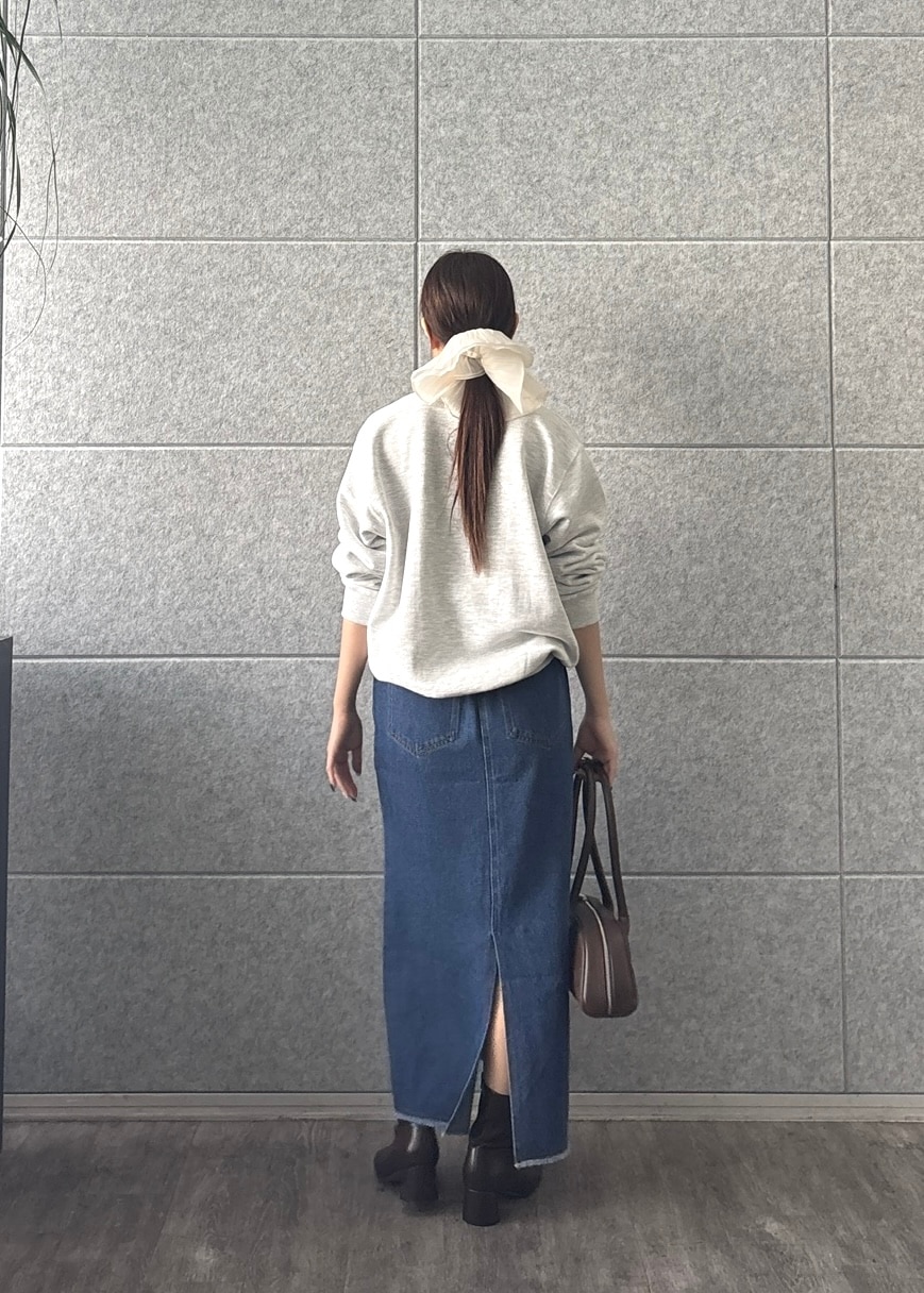 グレー系のスウェット、ブルー系のデニムスカート、シルバー系のネックレスを着用したレディースの秋コーディネートの5枚目の写真