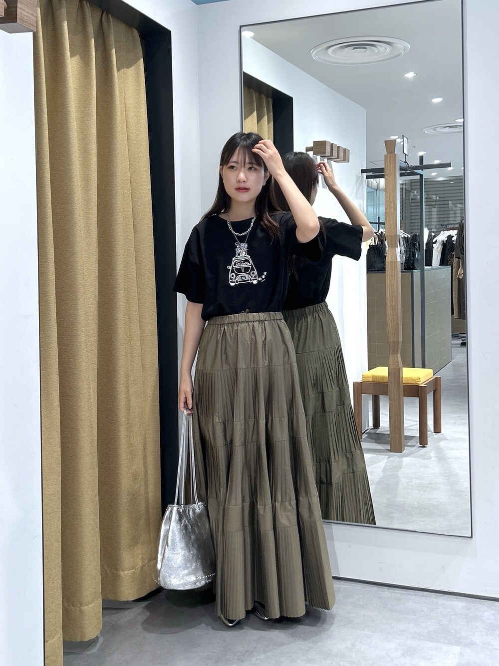ブラック系のTシャツ/カットソー、グリーン系のスカート、シルバー系のハンドバッグを着用したレディースの夏コーディネートの2枚目の写真