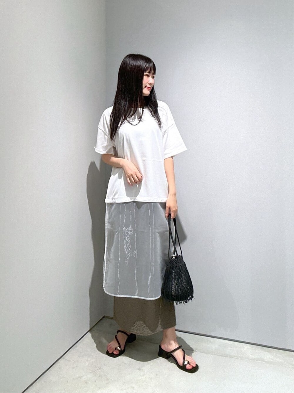 ホワイト系のTシャツ/カットソー、グリーン系のスカート、ブラック系のハンドバッグを着用したレディースの夏コーディネートの4枚目の写真
