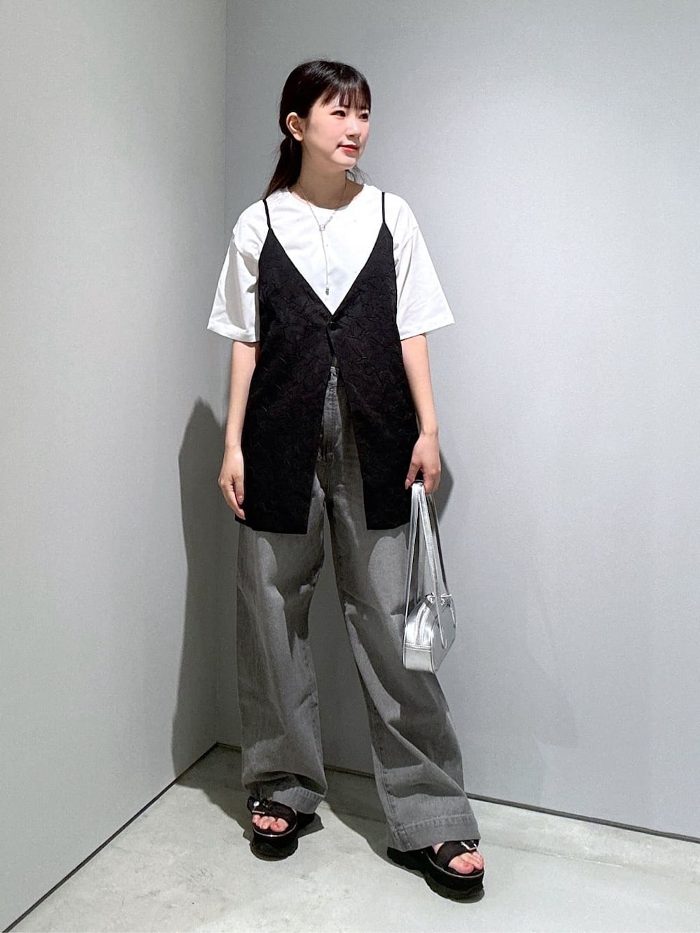 ホワイト系のTシャツ/カットソー、ブラック系のベスト、グレー系のデニムパンツを着用したレディースの夏コーディネートの2枚目の写真