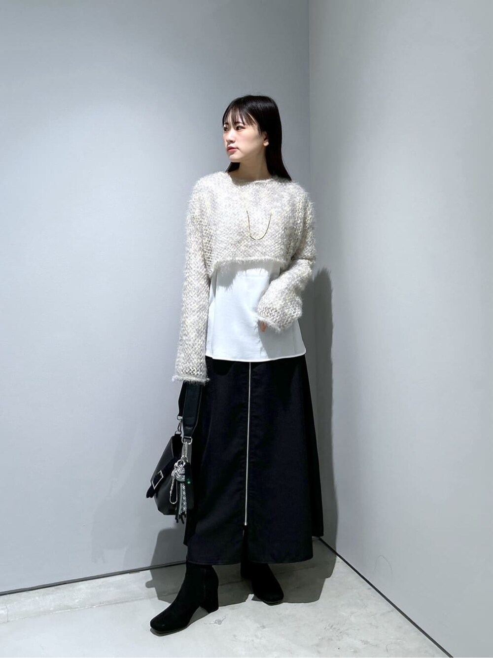 ベージュ系のニット/セーター、ホワイト系のシャツ/ブラウス、ブラック系のスカートを着用したレディースの冬コーディネートの2枚目の写真