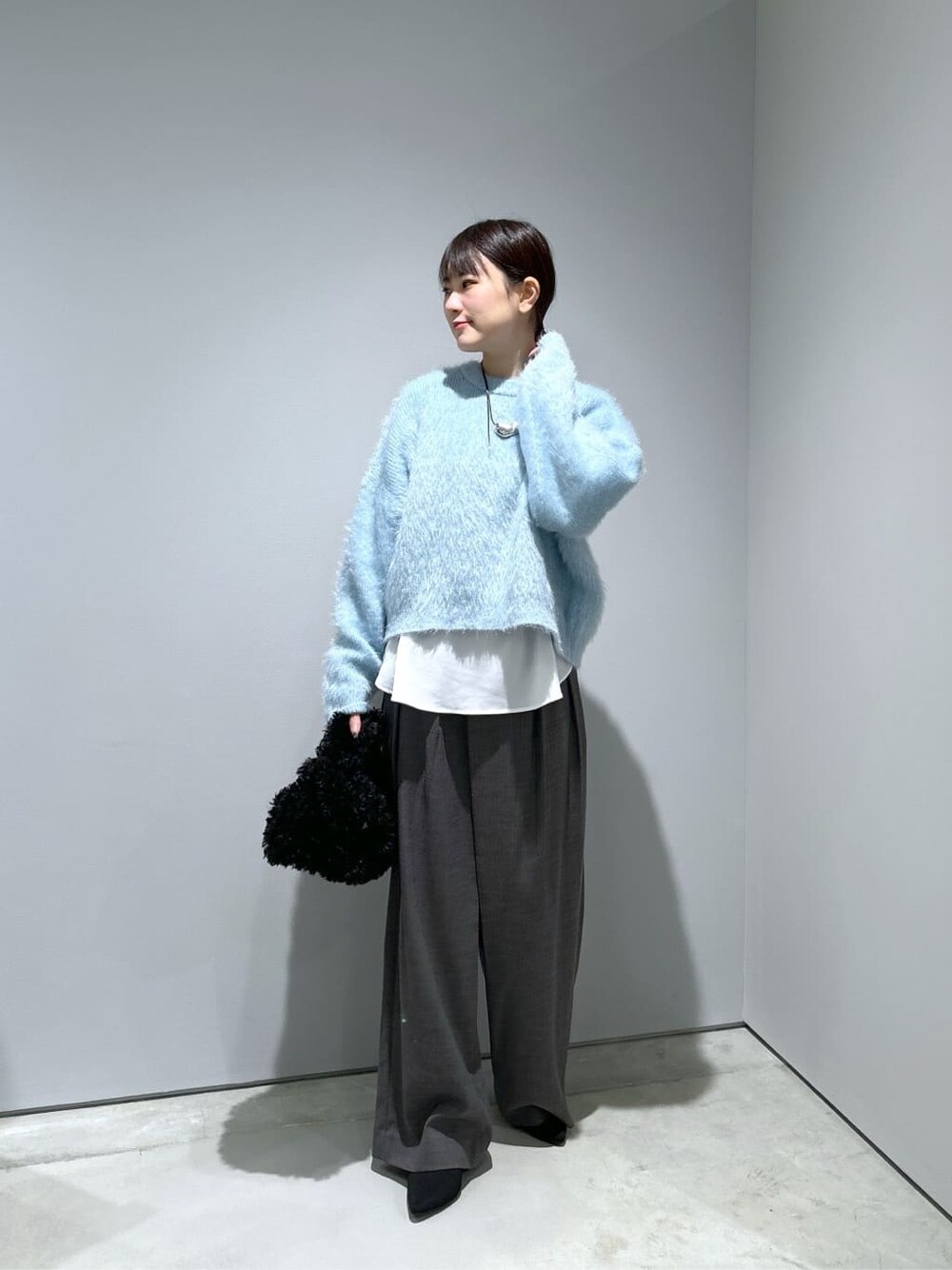 ブルー系のニット/セーター、ホワイト系のシャツ/ブラウス、グレー系のその他パンツを着用したレディースの秋コーディネートの4枚目の写真