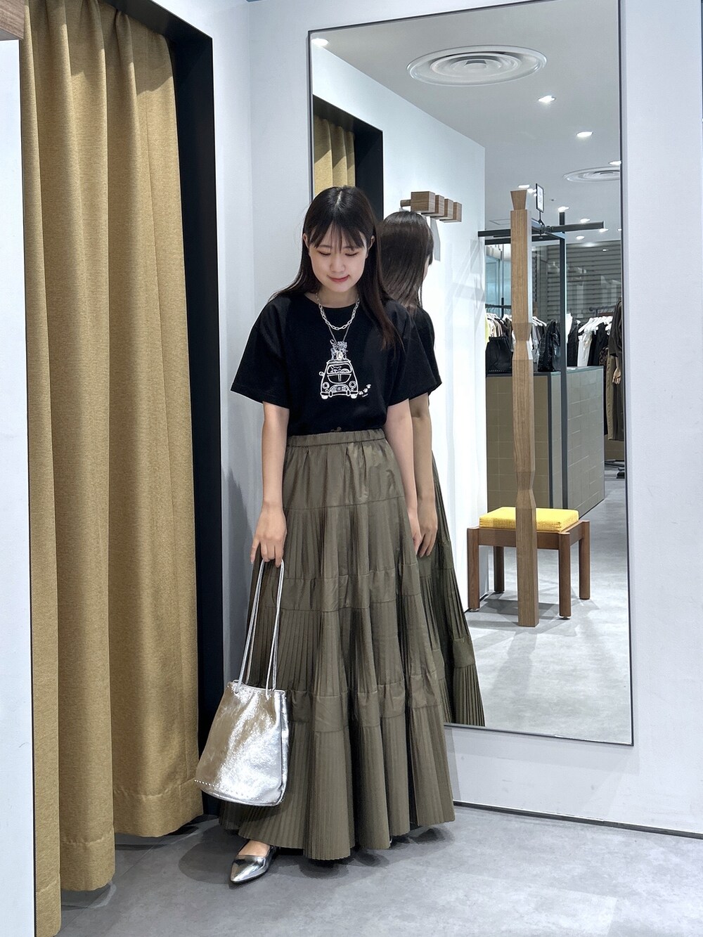 ブラック系のTシャツ/カットソー、グリーン系のスカート、シルバー系のハンドバッグを着用したレディースの夏コーディネートの3枚目の写真