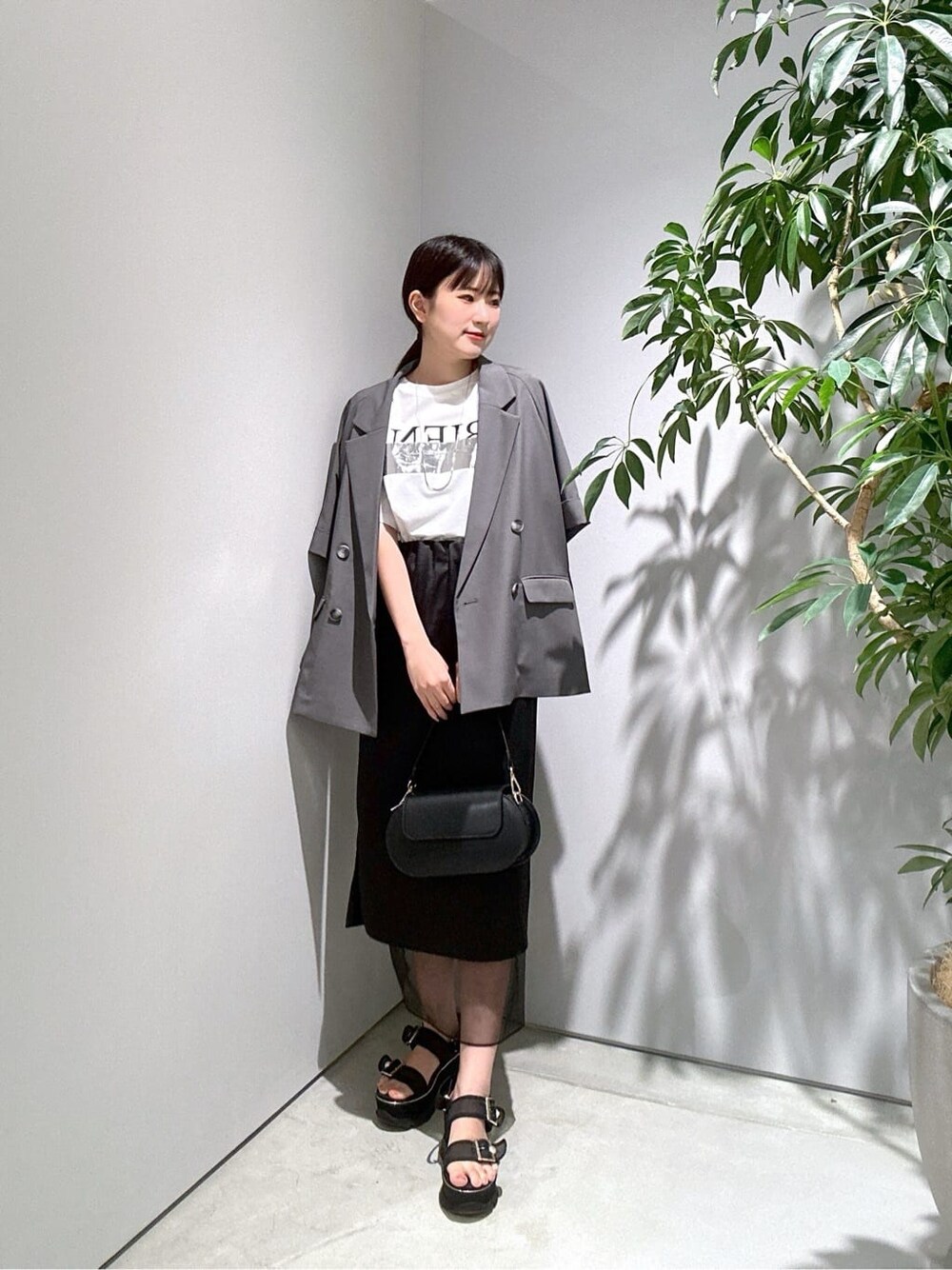 グレー系のテーラードジャケット、ホワイト系のTシャツ/カットソー、ブラック系のスカートを着用したレディースの夏コーディネートの2枚目の写真
