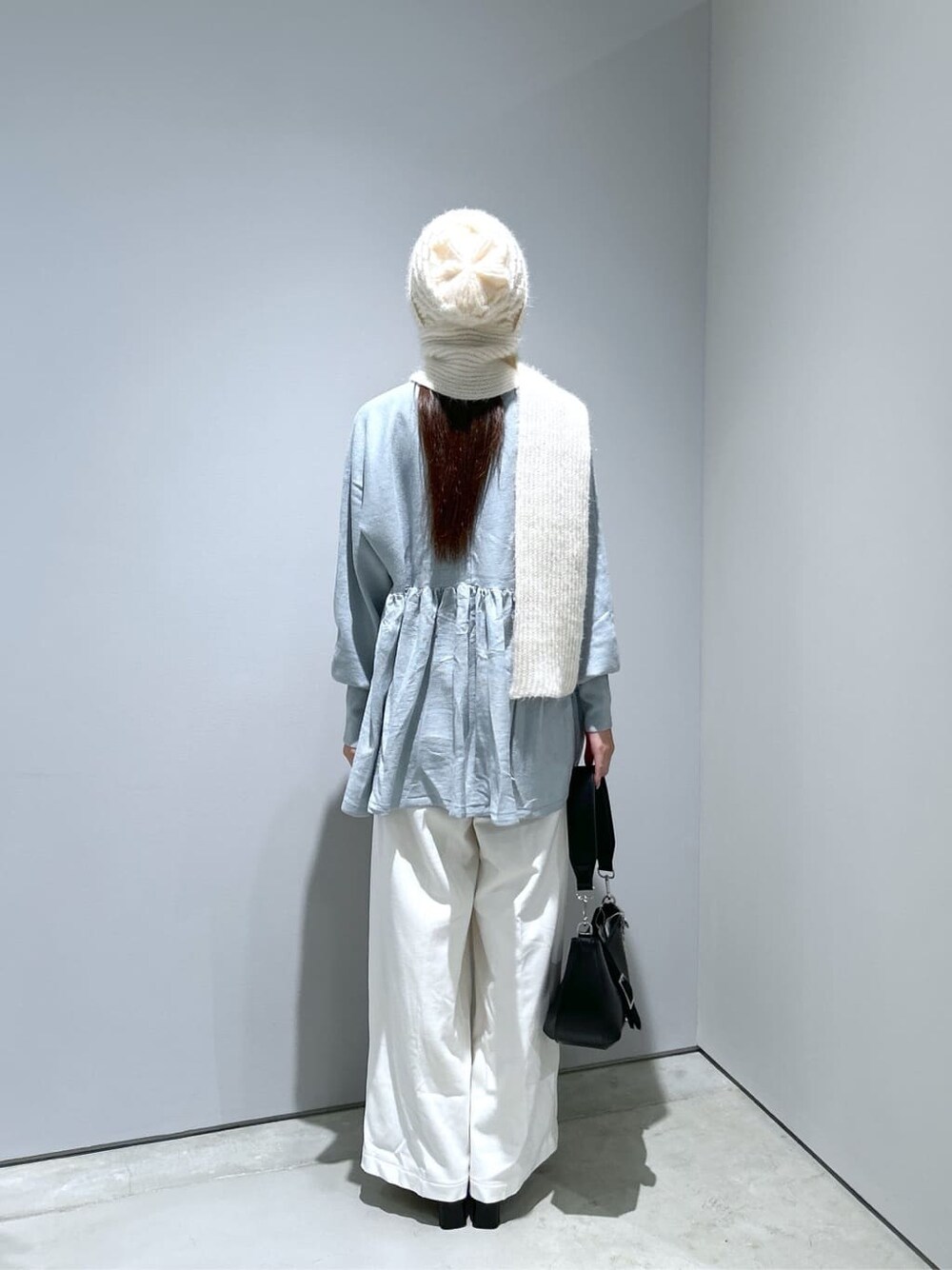 ブルー系のニット/セーター、ホワイト系のその他パンツ、ブラック系のショルダーバッグを着用したレディースの冬コーディネートの4枚目の写真
