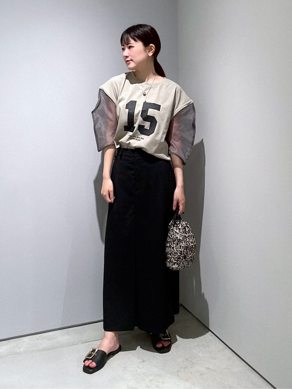 グリーン系のTシャツ/カットソー、ブラック系のスカート、ブラック系のハンドバッグを着用したレディースの夏コーディネートの4枚目の写真