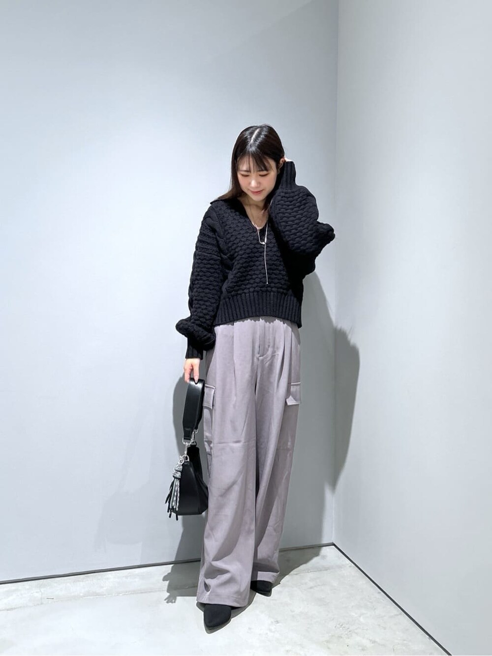ブラック系のニット/セーター、グレー系のその他パンツ、ブラック系のショルダーバッグを着用したレディースの秋コーディネートの4枚目の写真