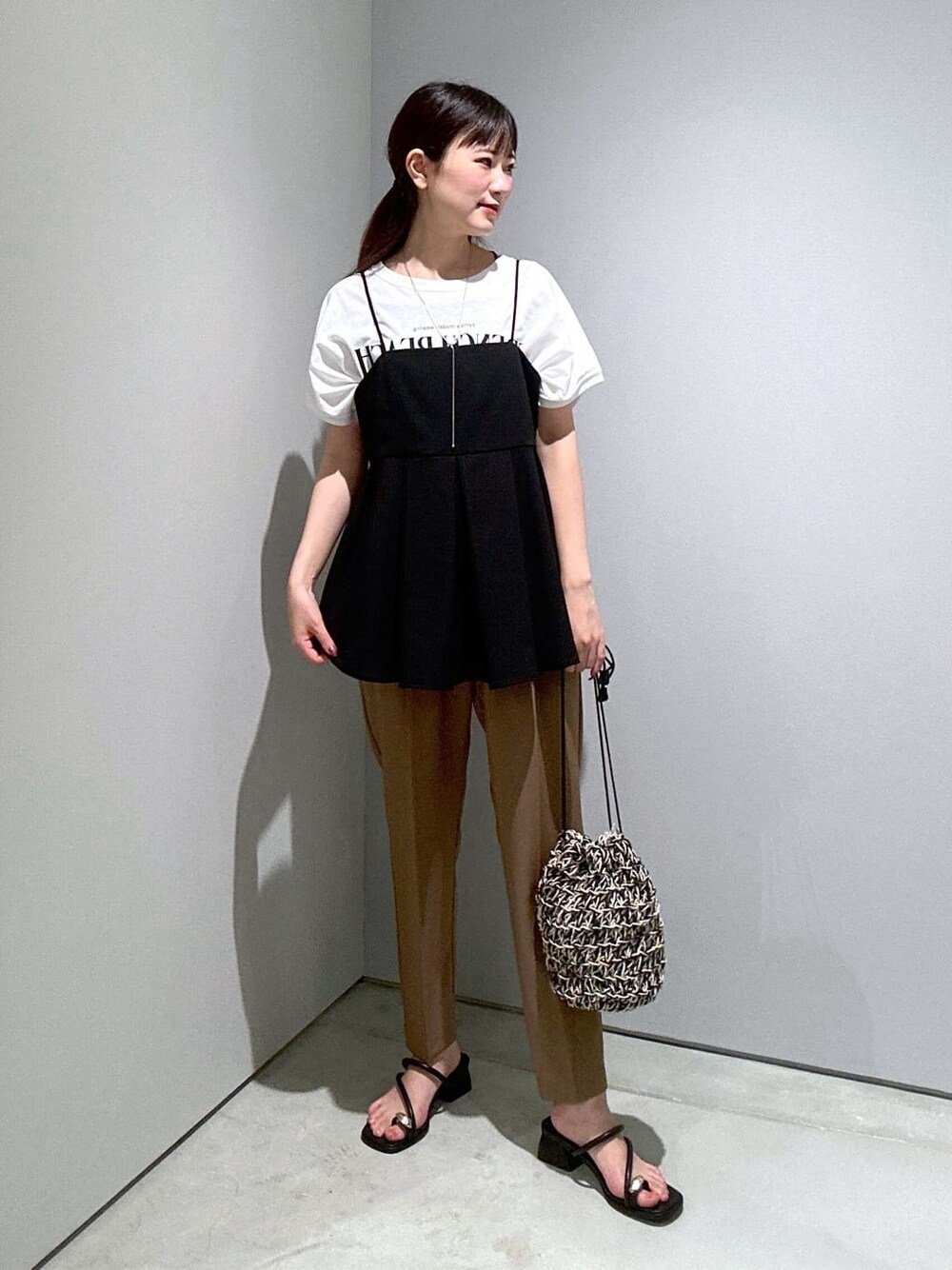 ブラック系のタンクトップ、イエロー系のその他パンツ、ブラック系のハンドバッグを着用したレディースの夏コーディネートの3枚目の写真