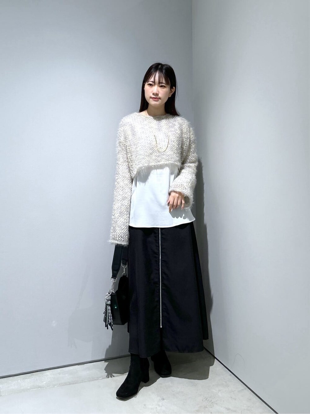 ベージュ系のニット/セーター、ホワイト系のシャツ/ブラウス、ブラック系のスカートを着用したレディースの冬コーディネートの3枚目の写真