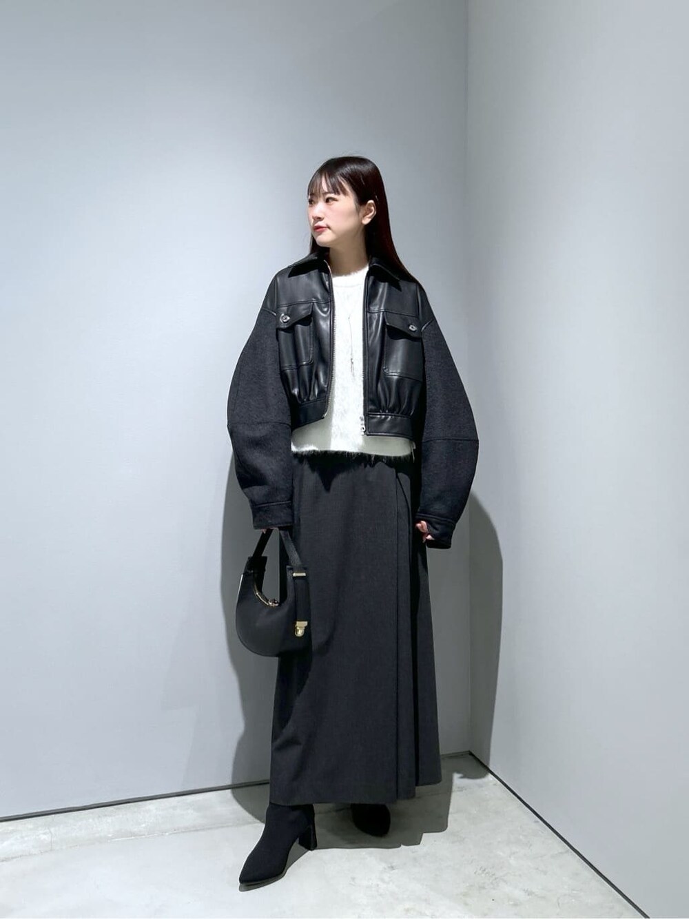 ブラック系のブルゾン、ホワイト系のニット/セーター、グレー系のスカートを着用したレディースの冬コーディネートの2枚目の写真