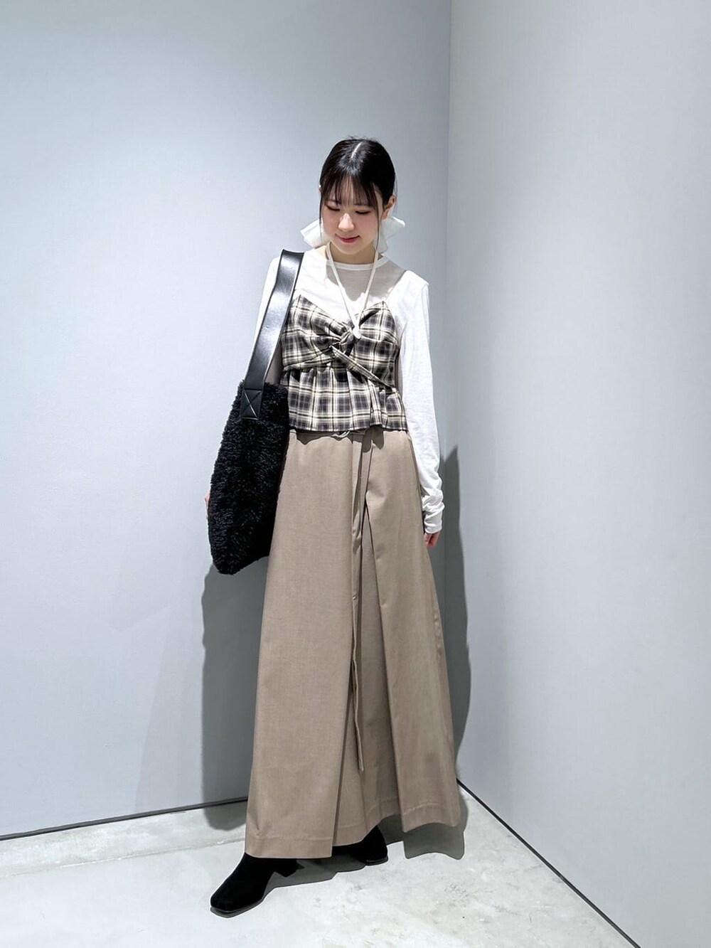 ベージュ系のタンクトップ、ホワイト系のTシャツ/カットソー、ベージュ系のスカートを着用したレディースの冬コーディネートの4枚目の写真