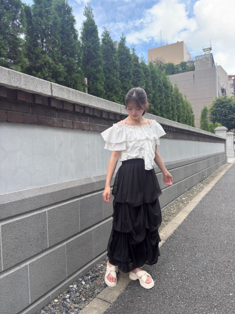 ブラック系のスカート、ホワイト系のシャツ/ブラウスを着用したレディースの夏コーディネートの2枚目の写真