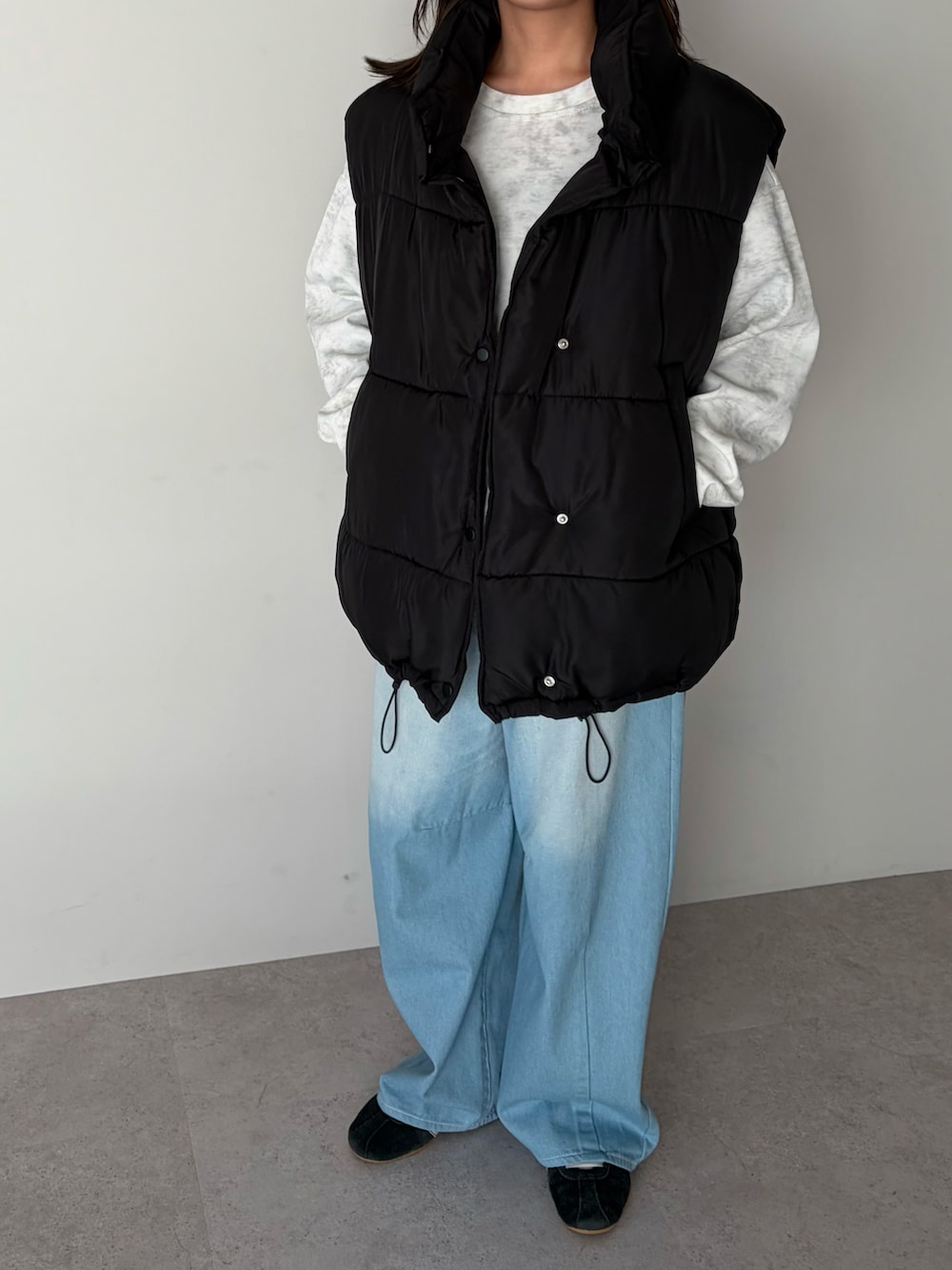 ホワイト系のスウェット、ブラック系のダウンベスト、ブラック系のスニーカーを着用したレディースの冬コーディネートの3枚目の写真