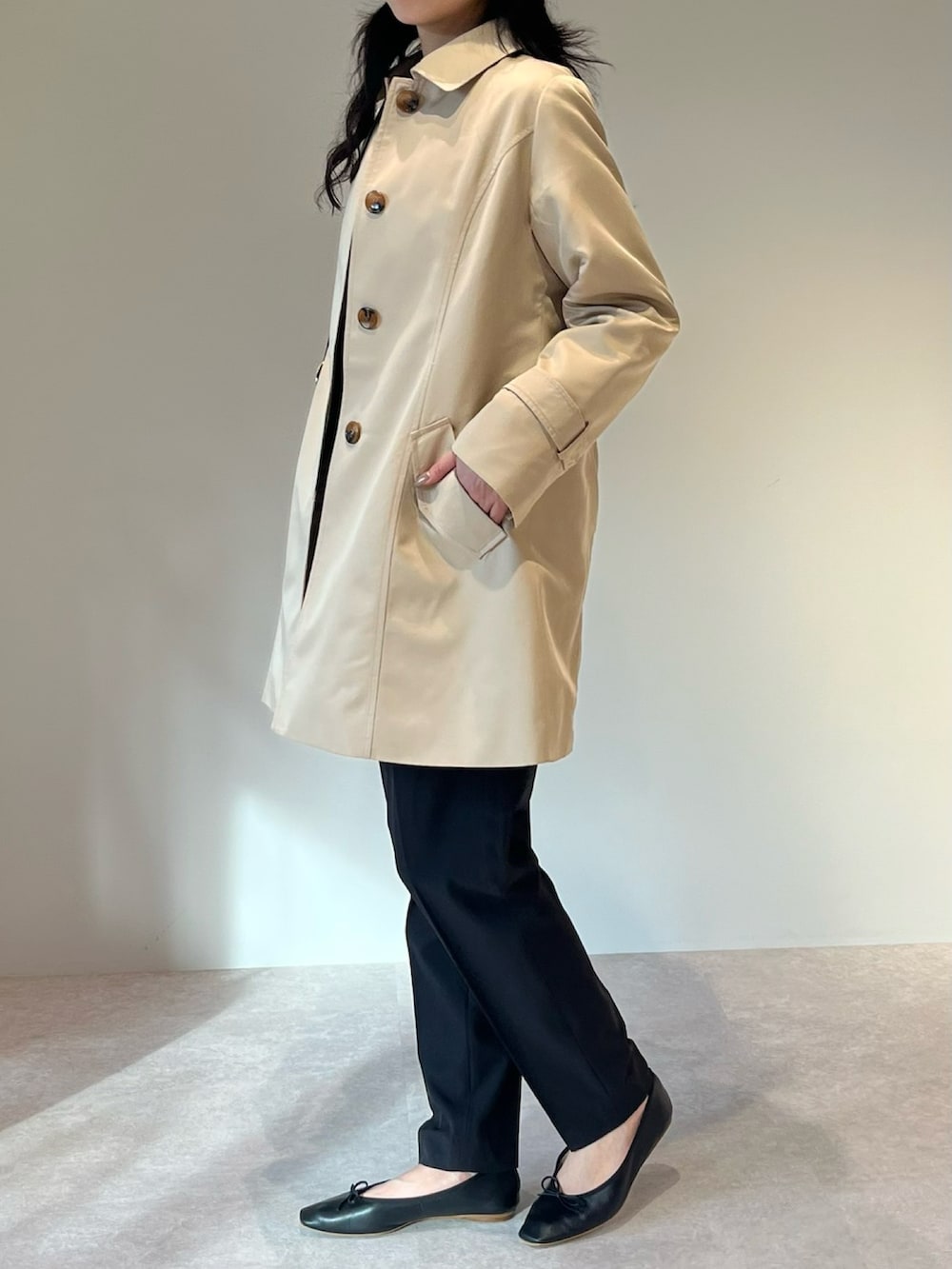 ブラウン系のトートバッグ、ブラック系のスーツセット、ベージュ系のトレンチコートを着用したレディースの冬コーディネートの2枚目の写真