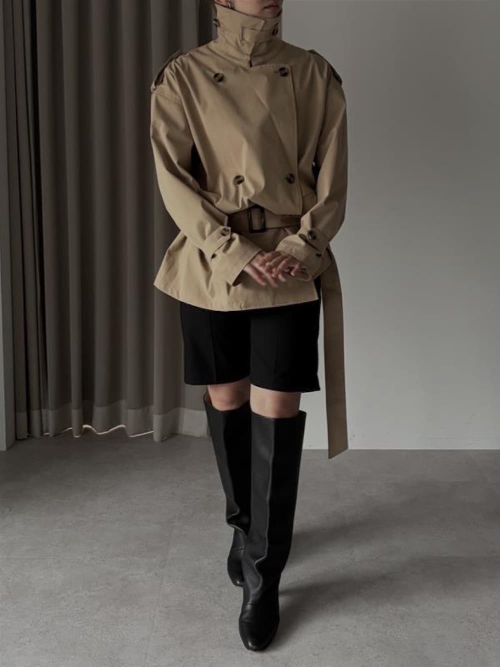 ベージュ系のトレンチコートを着用したレディースの冬コーディネートの2枚目の写真