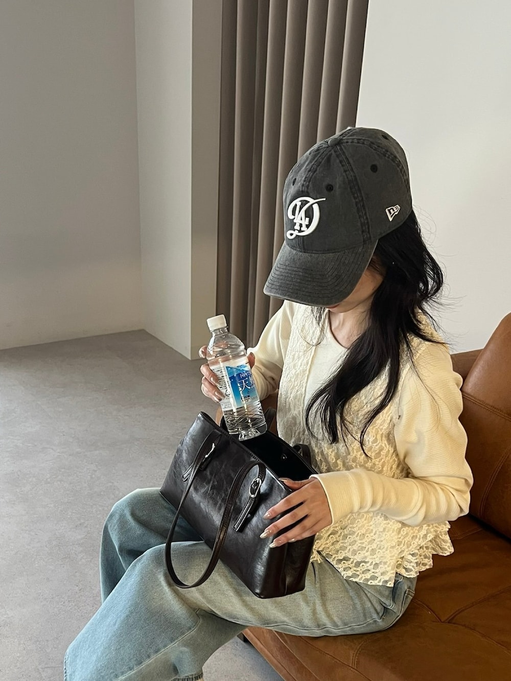 ホワイト系のベスト、ブラウン系のトートバッグ、ブルー系のデニムパンツを着用したレディースの冬コーディネートの2枚目の写真