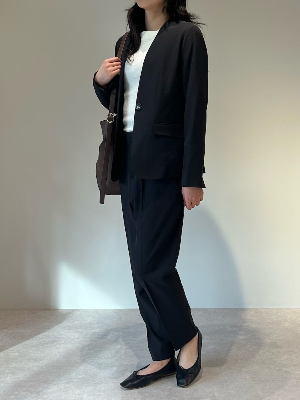 ブラウン系のトートバッグ、ブラック系のスーツセットを着用したレディースの冬コーディネートの2枚目の写真