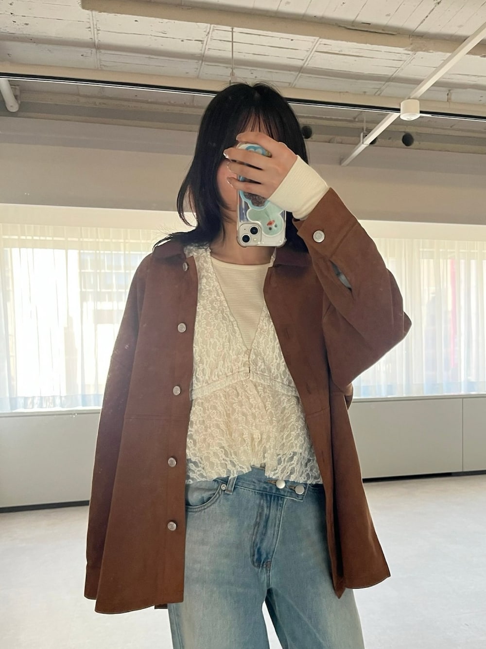 ブラウン系のシャツ/ブラウス、ホワイト系のベスト、ブルー系のデニムパンツを着用したレディースの冬コーディネートの3枚目の写真