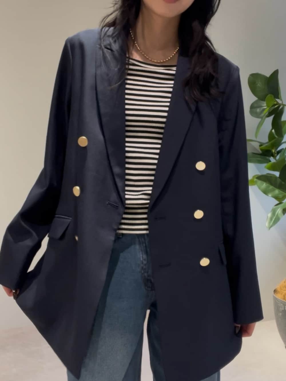 ブラウン系のハンドバッグ、ブルー系のテーラードジャケット、ゴールド系のネックレスを着用したレディースの冬コーディネートの3枚目の写真