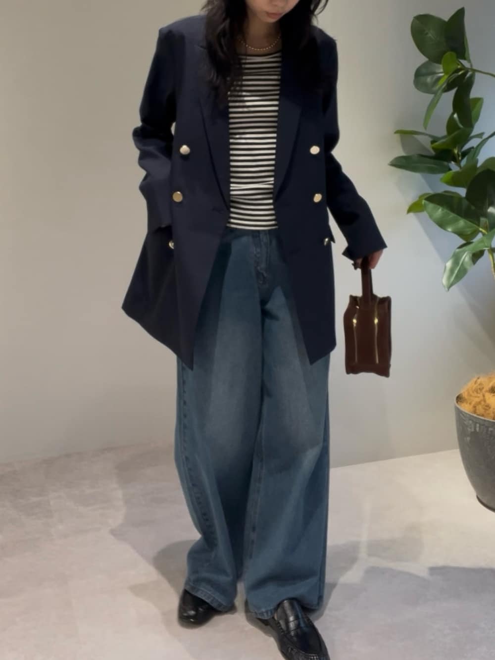 ブラウン系のハンドバッグ、ブルー系のテーラードジャケット、ゴールド系のネックレスを着用したレディースの冬コーディネートの2枚目の写真