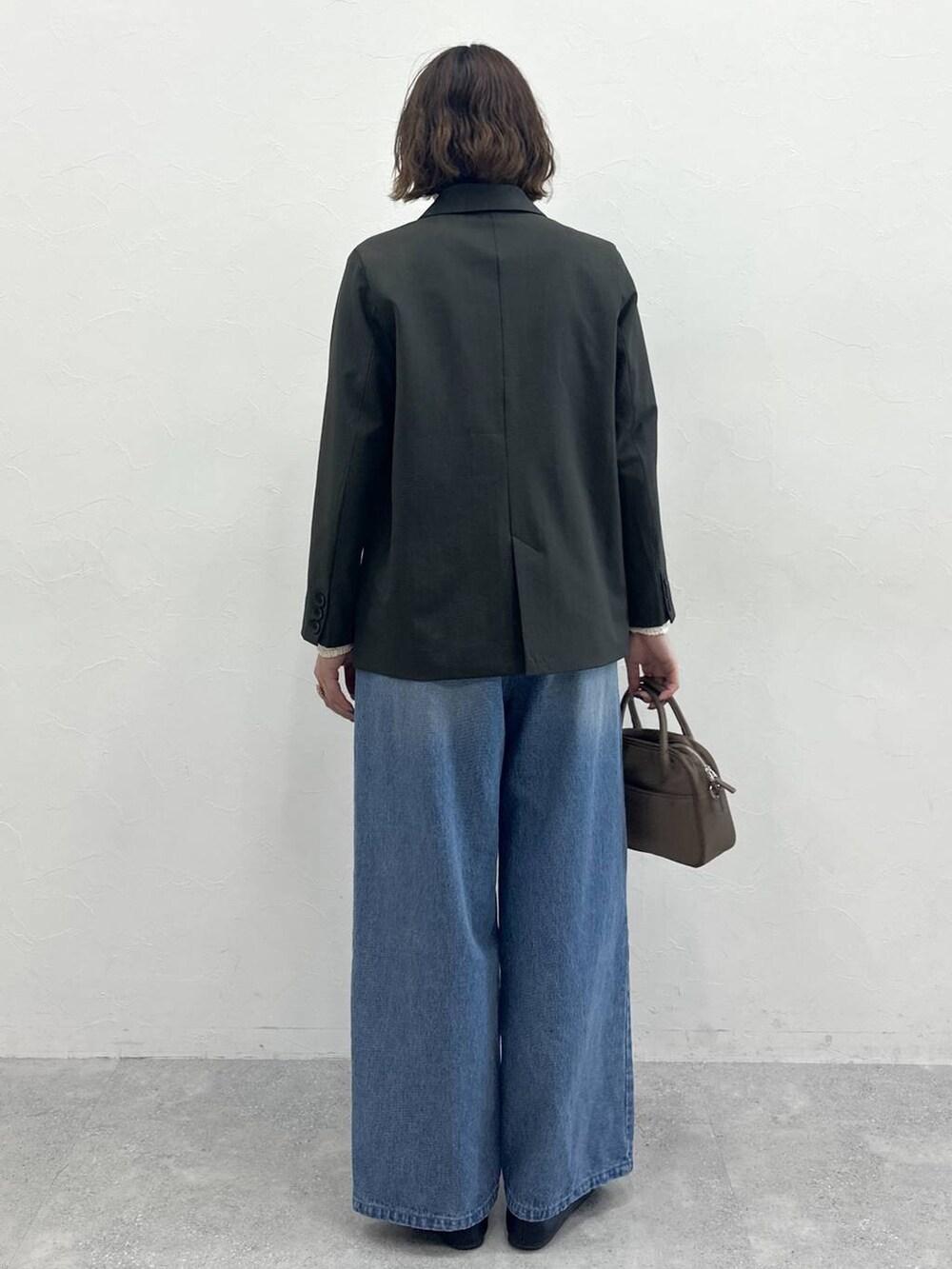 ブラウン系のハンドバッグ、グレー系のテーラードジャケット、ブルー系のデニムパンツを着用したレディースの春コーディネートの4枚目の写真